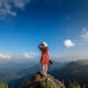 woman-hand-holding-camera-standing-top-rock-nature-travel-concept_335224-887